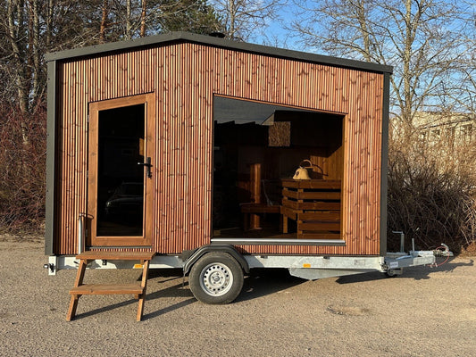 The Nomad mobile sauna on its braked road trailer, parked on gravel