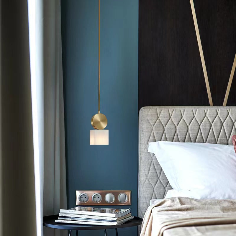 Gold pendant light with warm stone shade above bedside table in blue bedroom