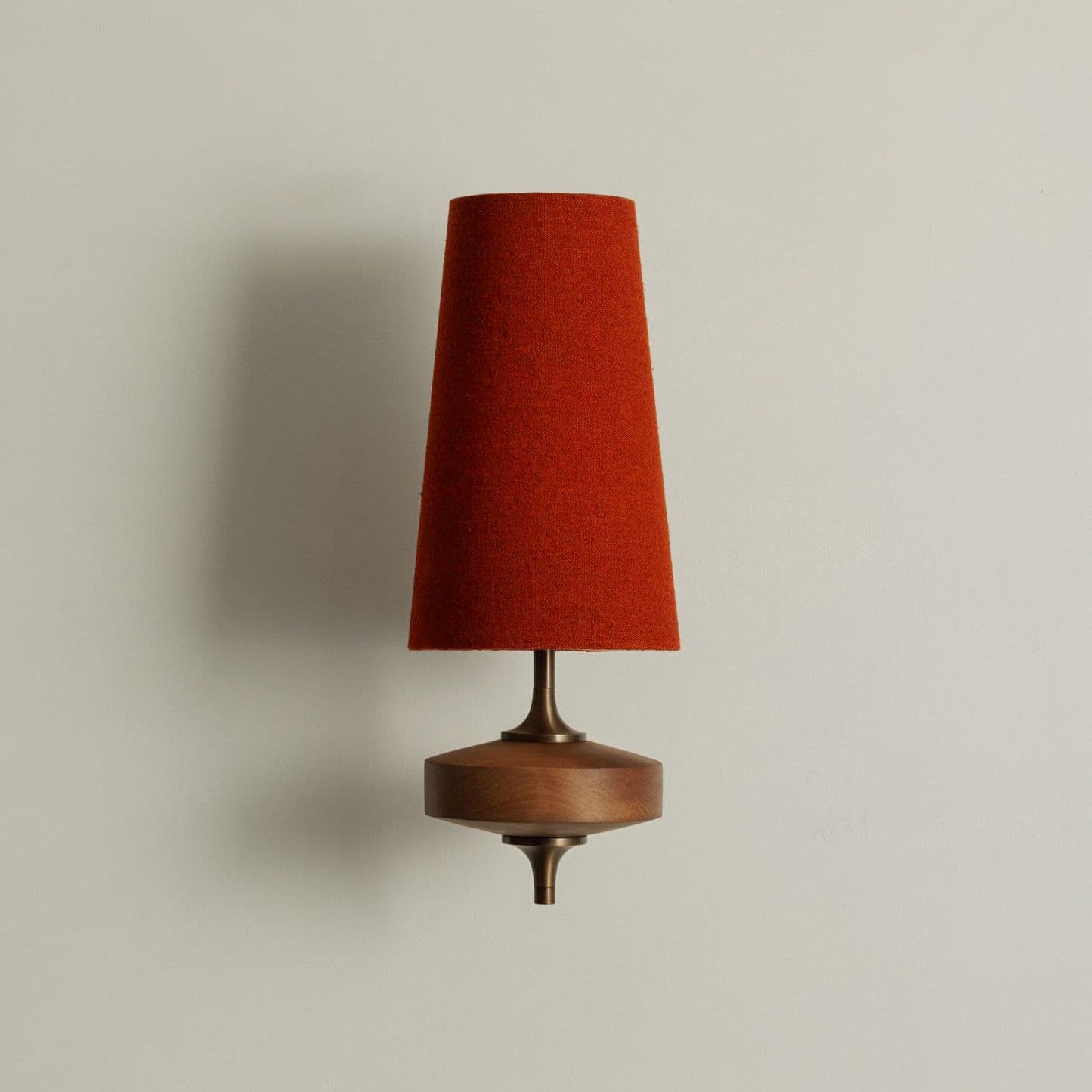 Single walnut and brass wall sconce with terracotta red linen shade