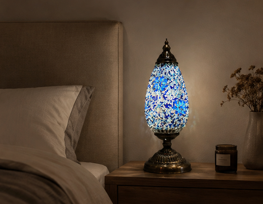 Serena Turkish mosaic table lamp lit on a wooden bedside table beside a bed in a warm bedroom