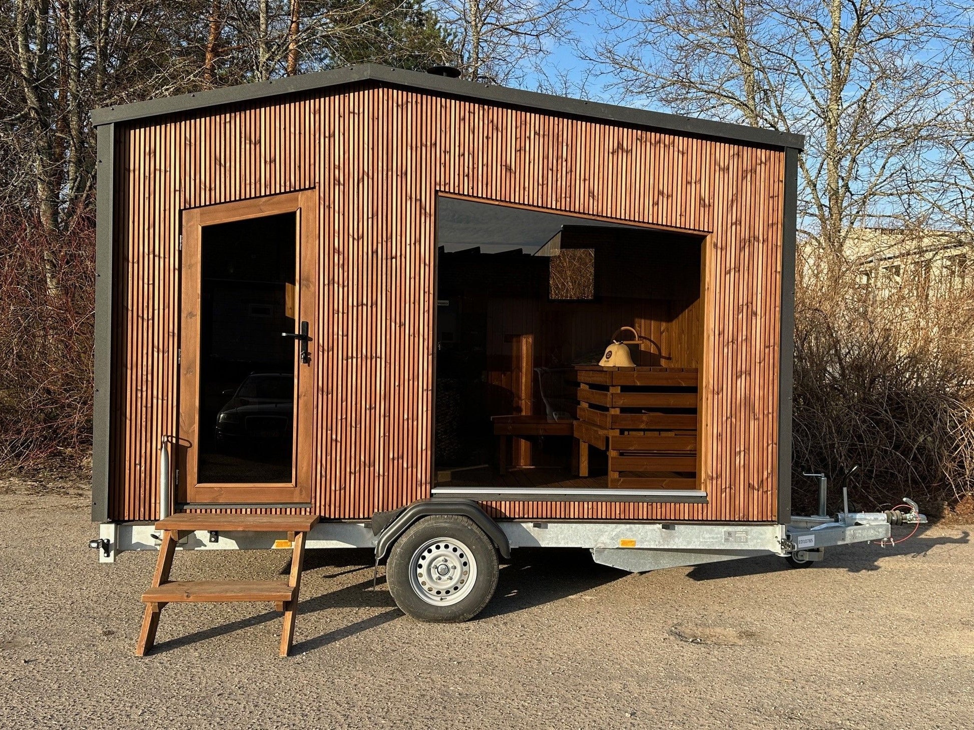 The Nomad mobile sauna on its braked road trailer, parked on gravel