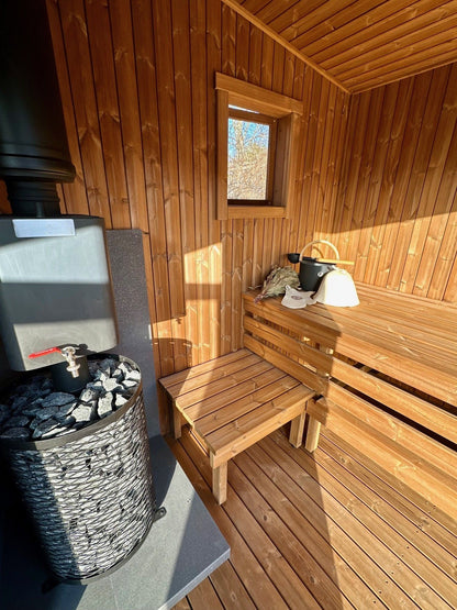 Inside the Nomad mobile sauna with thermo-wood benches and a wood-burning stove