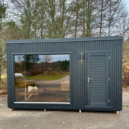 Modular building with glass wall and door in a forest setting