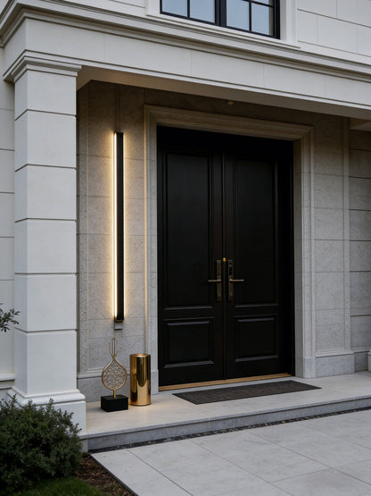 Modern black door with gold handle on a light gray building facade