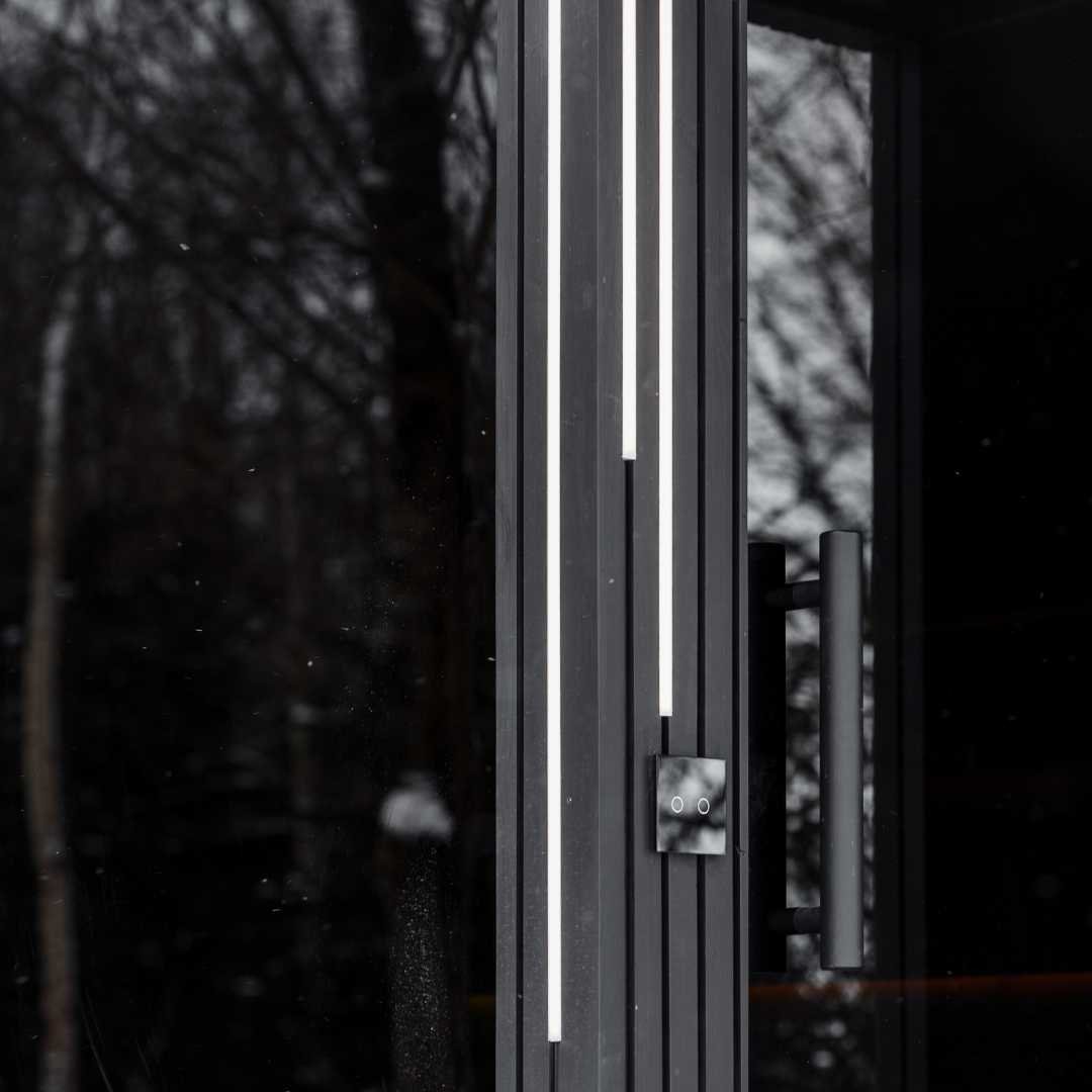 EBON outdoor sauna with shower, exterior at dusk with LED lighting lit