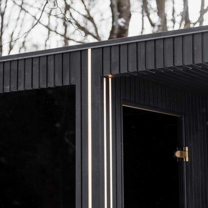EBON outdoor sauna with shower shown lit from inside in the evening
