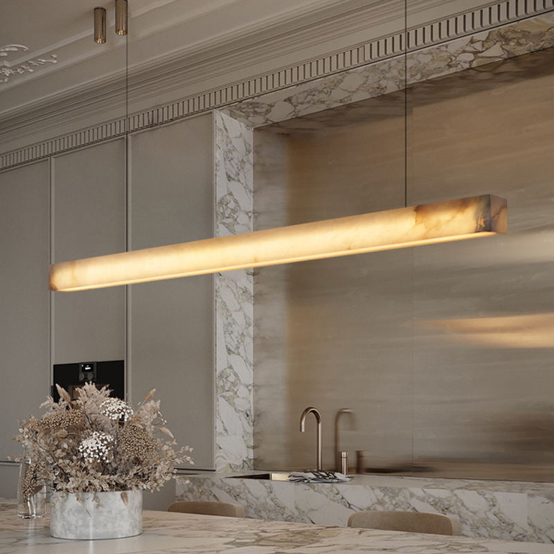 Linear alabaster-effect pendant light glowing above dining table