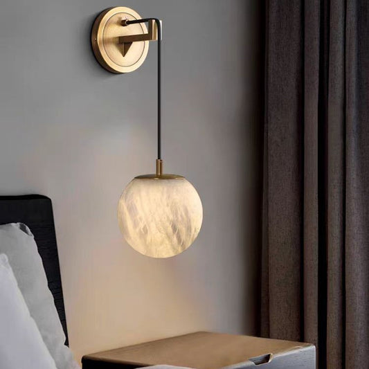 Recessed alabaster sphere wall light with brass surround glowing warm