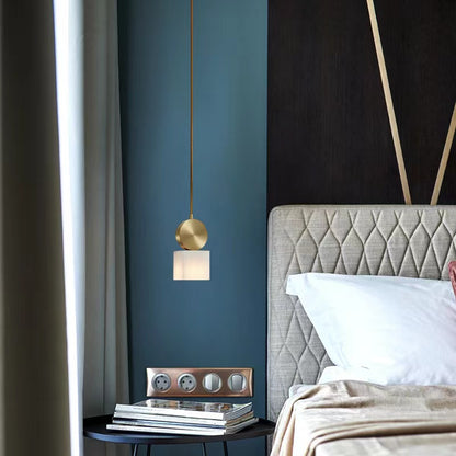 Gold pendant light with warm stone shade above bedside table in blue bedroom