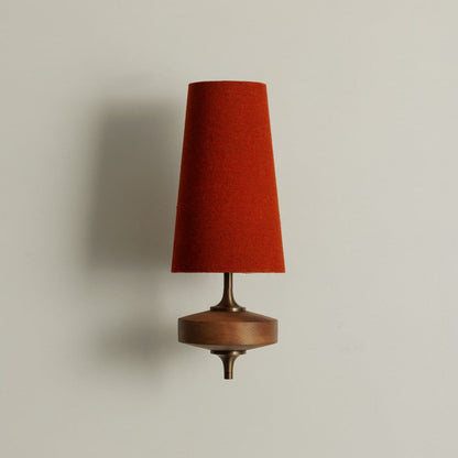 Single walnut and brass wall sconce with terracotta red linen shade