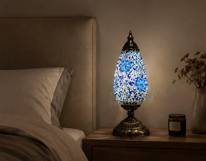 Serena Turkish mosaic table lamp lit on a wooden bedside table beside a bed in a warm bedroom