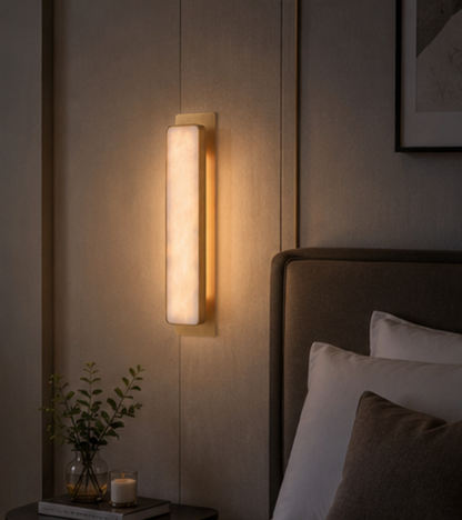 Torino marble wall sconce lit on an interior wall, showing the warm glow through the stone